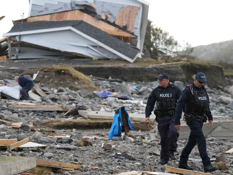 &copy; Reuters. شرطيان بالقرب من مبنى دمرته العاصفة فيونا في كندا يوم الاثنين. تصوير: جون موريس - رويترز. 