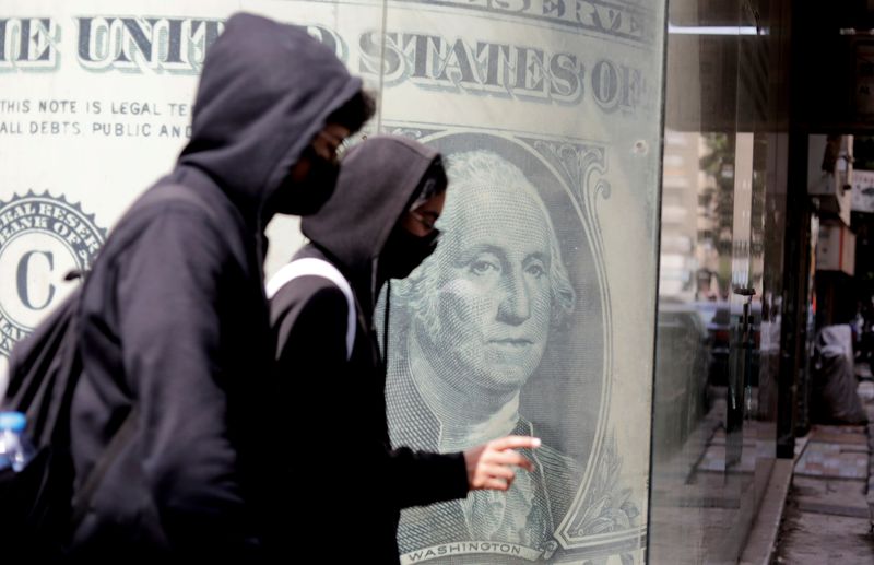 &copy; Reuters. FILE PHOTO: People walk past a currency exchange point, showing an image of the U.S. dollar in Cairo, Egypt,  March 22, 2022. REUTERS/Mohamed Abd El Ghany/File Photo