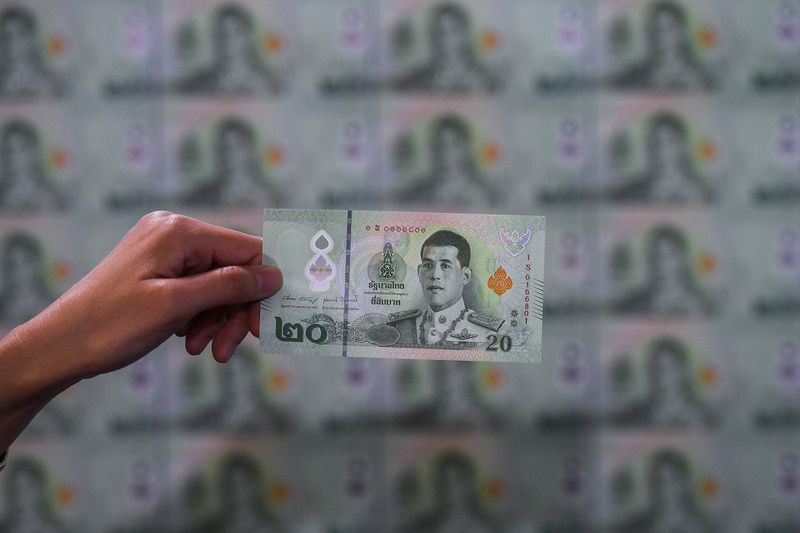 &copy; Reuters. FILE PHOTO: A man holds up a newly unveiled twenty baht polymer banknote at Bank of Thailand headquarters in Bangkok, Thailand, January 20, 2022. REUTERS/Chalinee Thirasupa