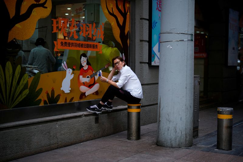 &copy; Reuters. سيدة صينية تتناول مثلجات الآيس كريم خارج أحد متاجر بيع الملابس في شنغهاي يوم الثلاثاء. تصوير: ألي سونج - رويترز 