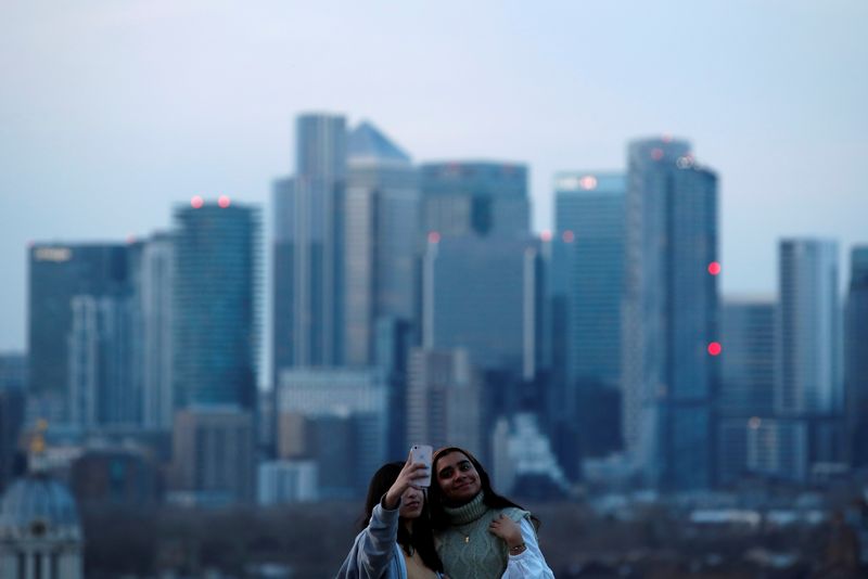 &copy; Reuters. FILE PHOTO: Women take a selfie overlooking Canary Wharf business district at dusk in London, Britain March 9, 2021. REUTERS/Peter Cziborra