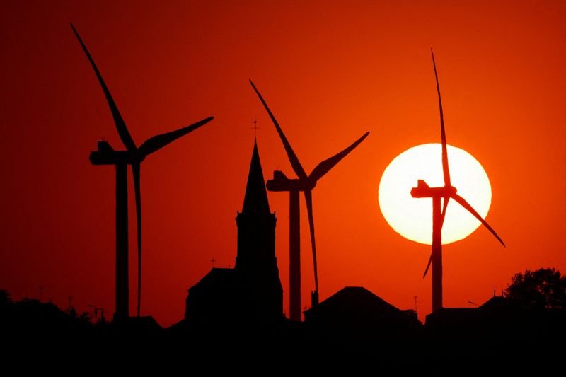 &copy; Reuters. Photo d'archives d'éoliennes et d'une église au coucher du soleil à Béthencourt. /Photo prise le 11 août 2022/REUTERS/Pascal Rossignol