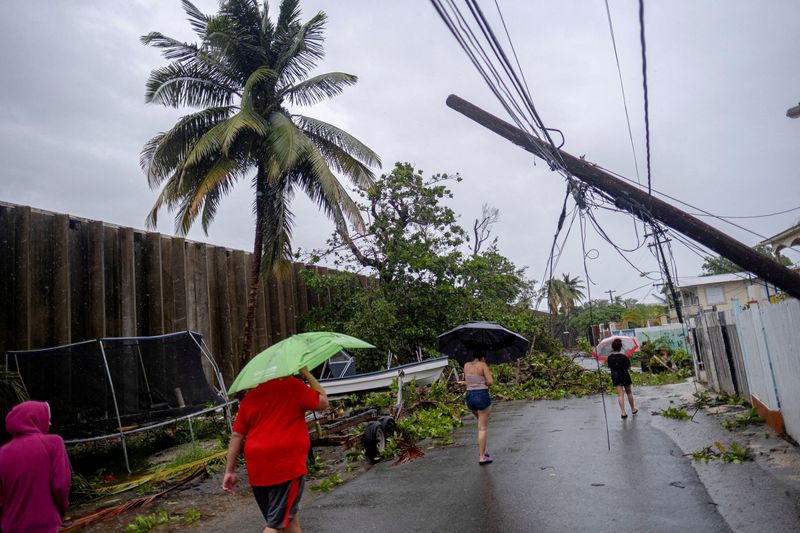 &copy; Reuters. FILE PHOTO: People walk on a street affected by the passing of Hurricane Fiona in Penuelas, Puerto Rico September 19, 2022.  REUTERS/Ricardo Arduengo/File Photo