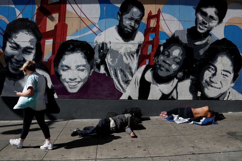 &copy; Reuters. FILE PHOTO: A woman walks past men passed out on the sidewalk n the Tenderloin area of San Francisco, California, U.S., February 28, 2020. Picture taken February 28, 2020. REUTERS/Shannon Stapleton/File Photo