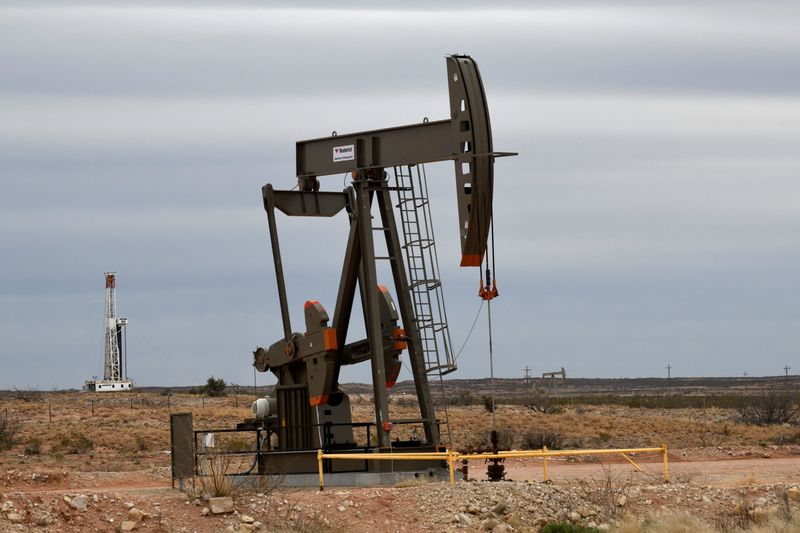 © Reuters. FILE PHOTO: A pump jack operates in front of a drilling rig owned by Exxon near Carlsbad, New Mexico, U.S. February 11, 2019. REUTERS/Nick Oxford