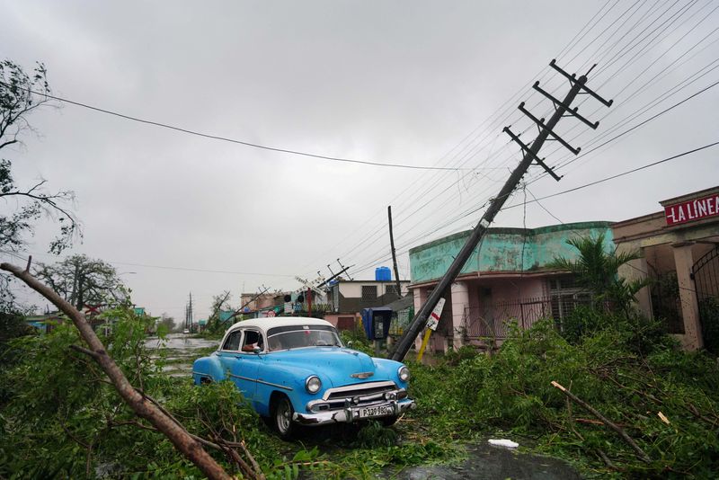 © Reuters. Un coche de época pasa junto a los escombros causados por el huracán Ian a su paso por Pinar del Río, Cuba. 27 de septiembre de 2022. REUTERS/Alexandre Meneghini  