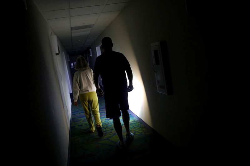 © Reuters. People walk in a hallway using a flashlight during a power outage as Hurricane Ian makes landfall in southwestern Florida, in Fort Myers, Florida, U.S. September 28, 2022. REUTERS/Marco Bello