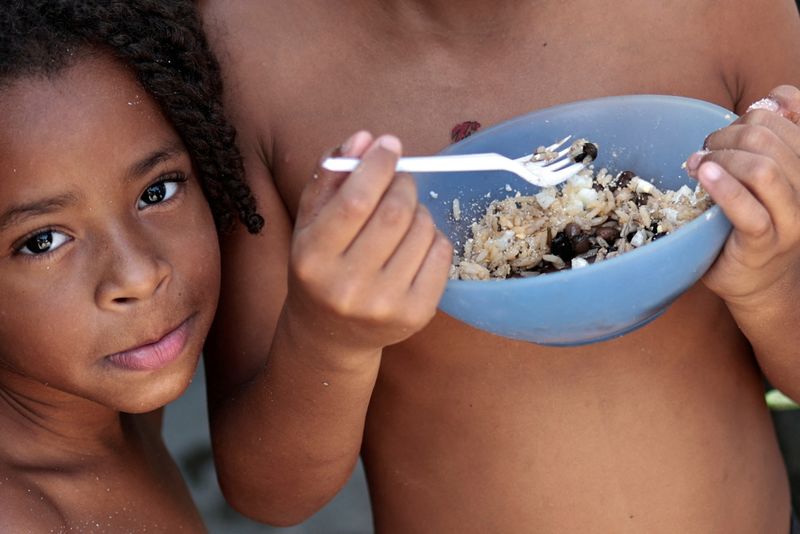 &copy; Reuters. Thawanny Silva de Souza, 6, (L) and Rafael Silva de Souza, 9, (R) eat a lunch of rice, beans and egg in their family's house, in the Arco Iris favela in Recife, Brazil, September 15, 2022. Rampant inflation and fallout from the pandemic have pushed food i