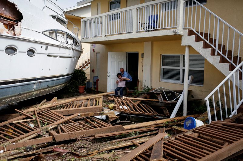 © Reuters. Un hombre ayuda a una mujer junto a un barco dañado en medio de un condominio del centro de la ciudad después de que el huracán Ian provocó una amplia destrucción, en Fort Myers, Florida, Estados Unidos. 29 de septiembre de 2022. REUTERS/Marco Bello  