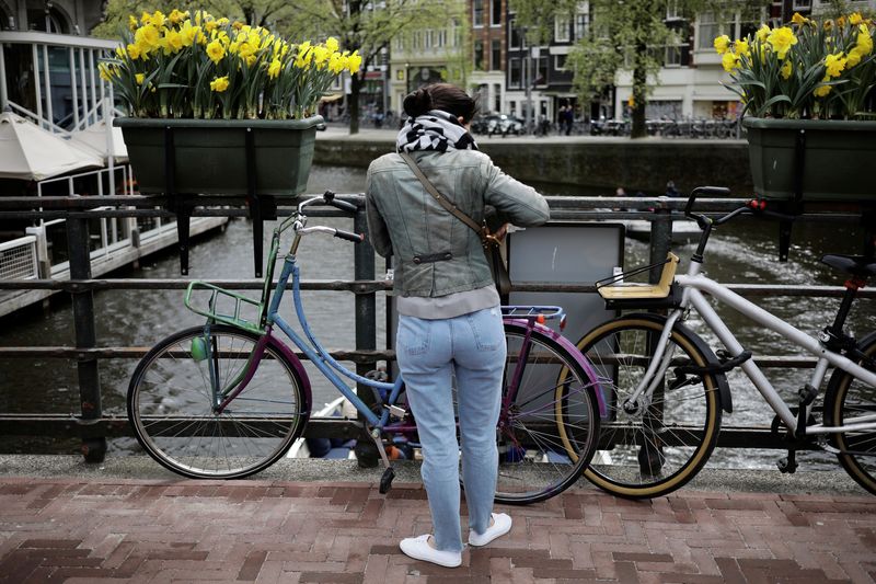 &copy; Reuters. FILE PHOTO: A woman parks her bike beneath boxes of daffodils on a bridge in Amsterdam, Netherlands April 22, 2017. REUTERS/Kevin Coombs