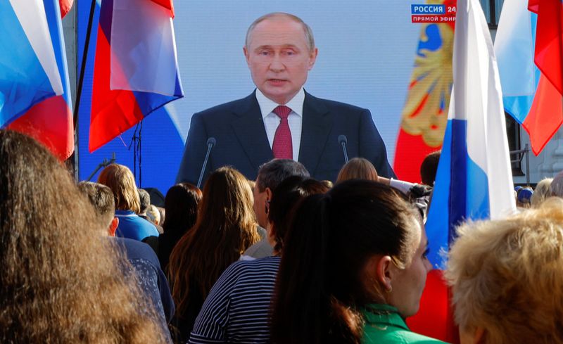 © Reuters. People gather near a screen showing Russian President Vladimir Putin during the broadcast of a ceremony to declare the annexation of the Russian-controlled territories of four Ukraine's Donetsk, Luhansk, Kherson and Zaporizhzhia regions, after holding what Russian authorities called referendums in the occupied areas of Ukraine that were condemned by Kyiv and governments worldwide, in Luhansk, Russian-controlled Ukraine, September 30, 2022. REUTERS/Alexander Ermochenko