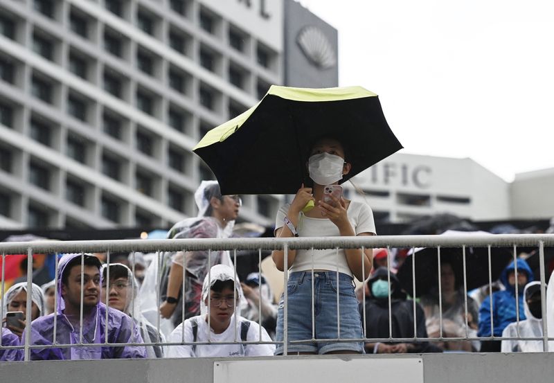 &copy; Reuters. متفرج يحمل مظلة للاحتماء من الأمطار الغزيرة قبل انطلاق سباق جائزة سنغافورة الكبرى ضمن بطولة العالم لسباقات فورمولا 1 للسيارات في صورة التقط