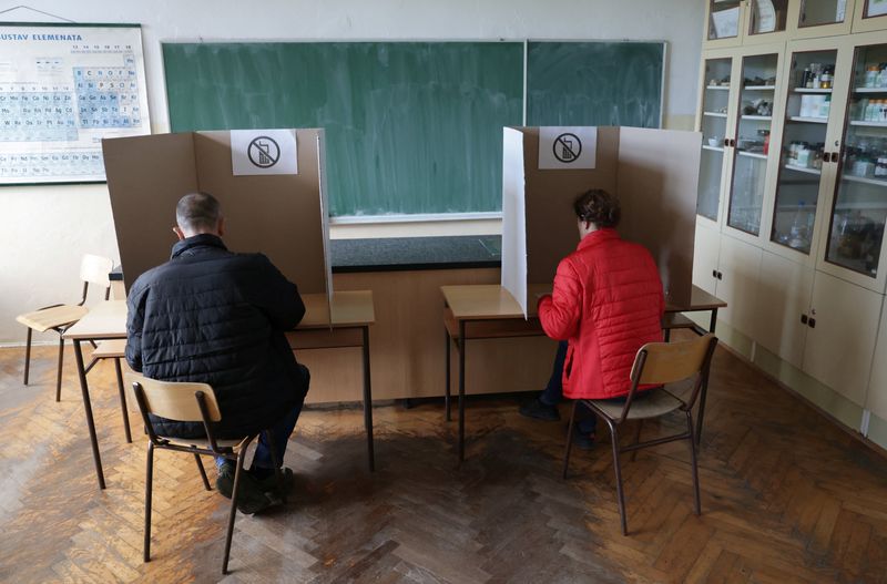 © Reuters. People hold a ballot in a voting booth during presidential and parliamentary elections at a polling centre in a school in Livno, Bosnia and Herzegovina October 2, 2022. REUTERS/Dado Ruvic