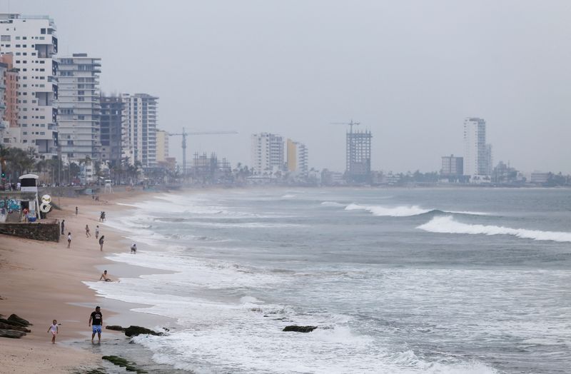 &copy; Reuters. أشخاص يسيرون على الشاطىء يوم الأحد بينما يقترب الإعصار أورلين من شاطىء منتجع مازالتان على شاطىء المحيط الهادي. تصوير : إدواردو ريسنديس- رويت