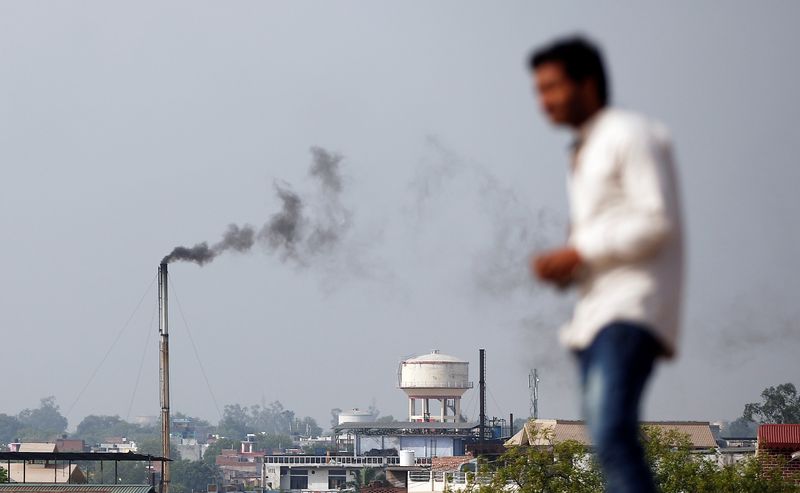 &copy; Reuters. FILE PHOTO: A man stands on a hill as smoke emits from a chimney of a leather tannery at an industrial area in Kanpur, India, May 4, 2018.  REUTERS/Adnan Abidi
