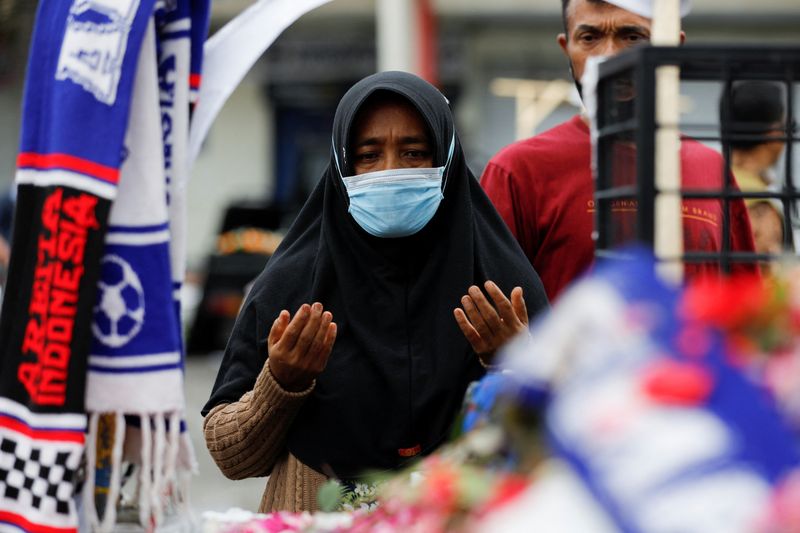© Reuters. امرأة تدعو لضحايا التدافع في مباراة محلية لكرة القدم في مالانج إندونيسيا يوم الاثنين. تصوير: ويلي كورنياوان - رويترز