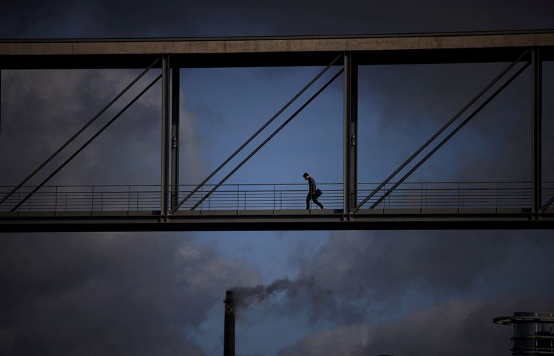 © Reuters. FILE PHOTO: Smoke rises from a chimney as a person crosses a bridge between the buildings of Germany's Bundestag, in Berlin, Germany, April 5, 2022. REUTERS/Lisi Niesner    