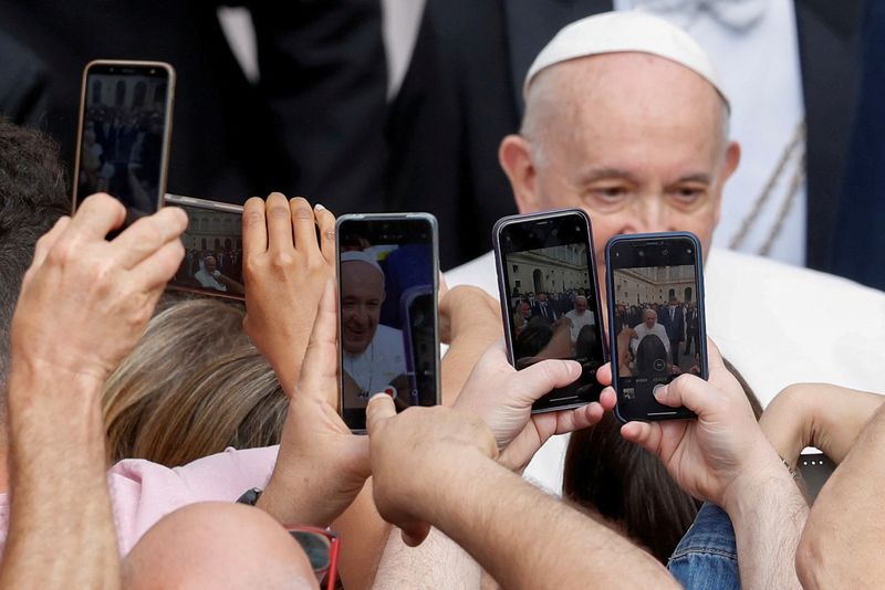 &copy; Reuters. FILE PHOTO: People use their phone cameras as Pope Francis arrives for his weekly general audience, at the San Damaso courtyard at the Vatican, June 2, 2021. REUTERS/Yara Nardi/File Photo