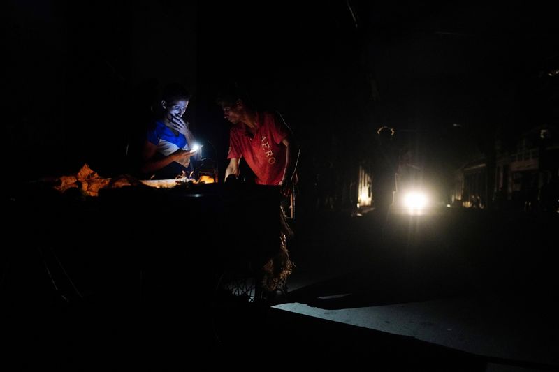 &copy; Reuters. Vendedores ambulantes utilizan la luz de un teléfono móvil durante un apagón tras el paso del huracán Ian en La Habana, Cuba, el 29 de septiembre2022. REUTERS/Alexandre Meneghini/Foto de Archivo