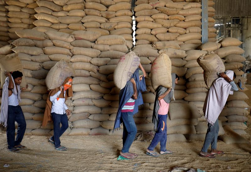 &copy; Reuters. FILE PHOTO: Workers carry sacks of wheat for sifting at a grain mill on the outskirts of Ahmedabad, India, May 16, 2022. REUTERS/Amit Dave/File Photo