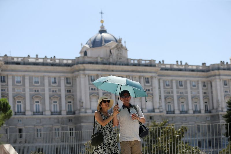 &copy; Reuters. FOTO DE ARCHIVO. Turistas se resguardan del sol bajo una sombrilla cerca del Palacio Real durante un día caluroso con temperaturas que alcanzan los 37 grados centígrados en Madrid, España. 9 de agosto de 2022. REUTERS/Isabel Infantes