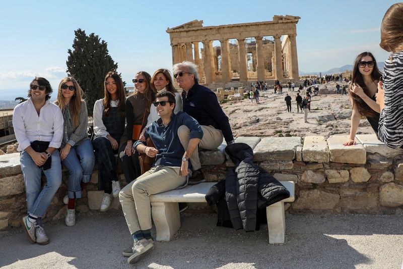 &copy; Reuters. FILE PHOTO: Visitors pose for a photo with the ancient Parthenon Temple seen in the background, atop the Acropolis hill archaeological site in Athens, Greece, February 26, 2022. Picture taken February 26, 2022. REUTERS/Louiza Vradi/File Photo Visitors pos