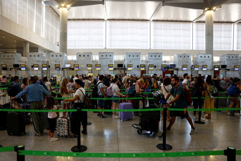 © Reuters. FILE PHOTO: Vueling passengers queue at check-in desks at Malaga-Costa del Sol Airport in Malaga, Spain, June 30, 2022. REUTERS/Jon Nazca/File Photo