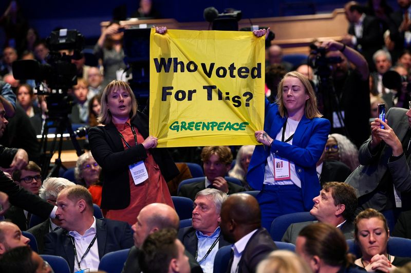 © Reuters. People hold up a sign in protest during British Prime Minister Liz Truss's speech, during Britain's Conservative Party's annual conference in Birmingham, Britain, October 5, 2022. REUTERS/Toby Melville