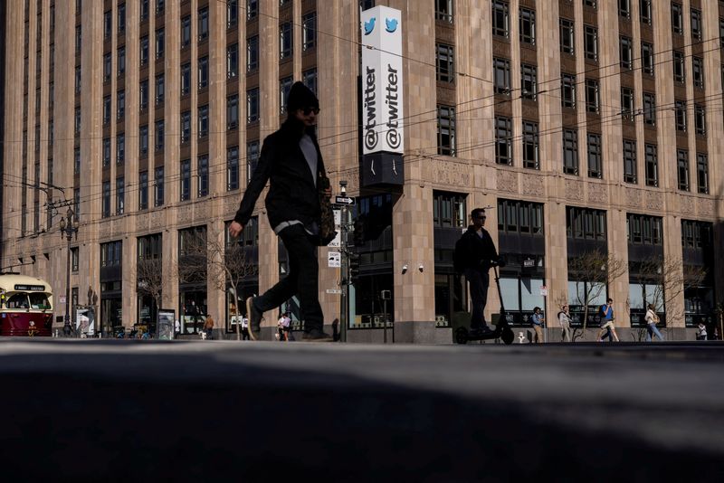 © Reuters. FILE PHOTO: People walk by a Twitter logo at the company headquarters in downtown San Francisco, California, U.S., April 25, 2022. REUTERS/Carlos Barria/File Photo