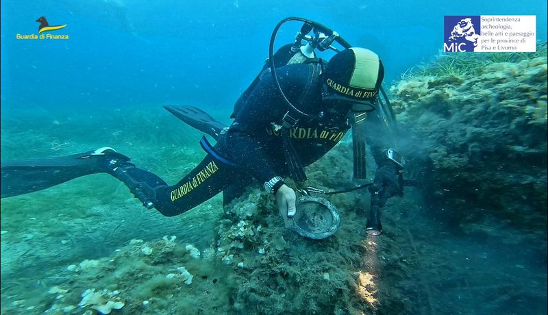 &copy; Reuters. Un agente de la Guardia di Finanza sostiene un cuenco decorado que data del siglo XIII y que ha sido recuperado en la costa de la Toscana, Italia, en esta foto distribuida sin fecha obtenida por Reuters el 5 de octubre de 2022. Guardia di Finanza/Handout 