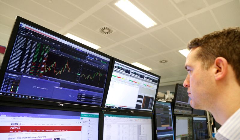 © Reuters. FILE PHOTO: A trader works at his desk whilst screens show market data at CMC Markets in London, Britain, January 16, 2019. REUTERS/John Sibley/File Photo