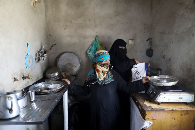 &copy; Reuters. أم هاني الشرعبي تشير إلى أطباق فارغة بينما تقف مع زوجة ابنها أم زكريا في مطبخها بصنعاء في اليمن في صورة بتاريخ السابع من سبتمبر أيلول 2022. تصو