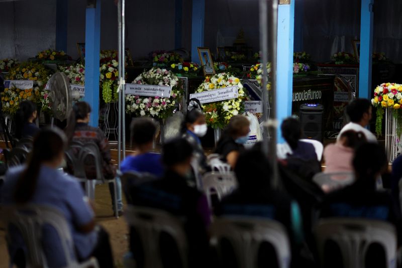 &copy; Reuters. أقارب يجلسون بالقرب من نعوش الضحايا في منطقة أوتاي ساوان في تايلاند يوم الجمعة. تصوير: أثيت بيراونجميثا - رويترز.