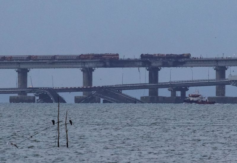 © Reuters. A passenger train approaches fuel tanks burnt on the Kerch bridge, after an explosion destroyed part of it, in the Kerch Strait, Crimea, October 9, 2022.  REUTERS/Alexey Pavlishak