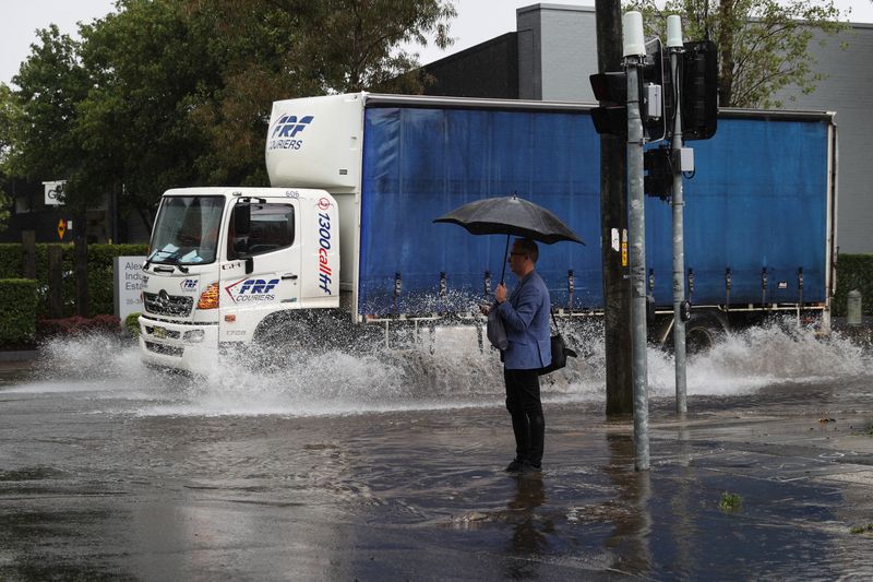 &copy; Reuters. FILE PHOTO: A pedestrian stands on the corner of a flooded street as heavy rains affect Sydney, Australia, October 6, 2022.  REUTERS/Loren Elliott