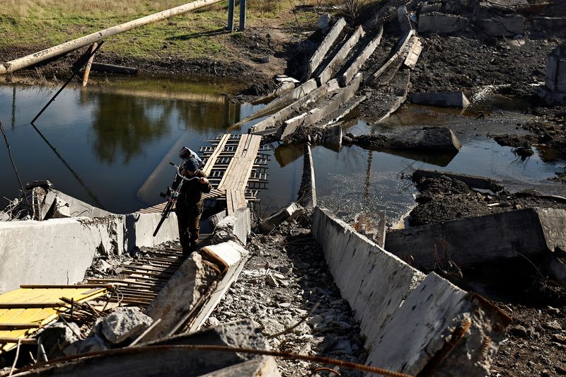 © Reuters. أحد السكان المحليين يحمل دراجة هوائية لدى عبوره أنقاض جسر دُمر في القتال بين القوات الروسية والجيش الأوكراني في بخموت يوم السادس من أكتوبر تشرين الأول 2022. تصوير: زهرة بن سمرة - رويترز