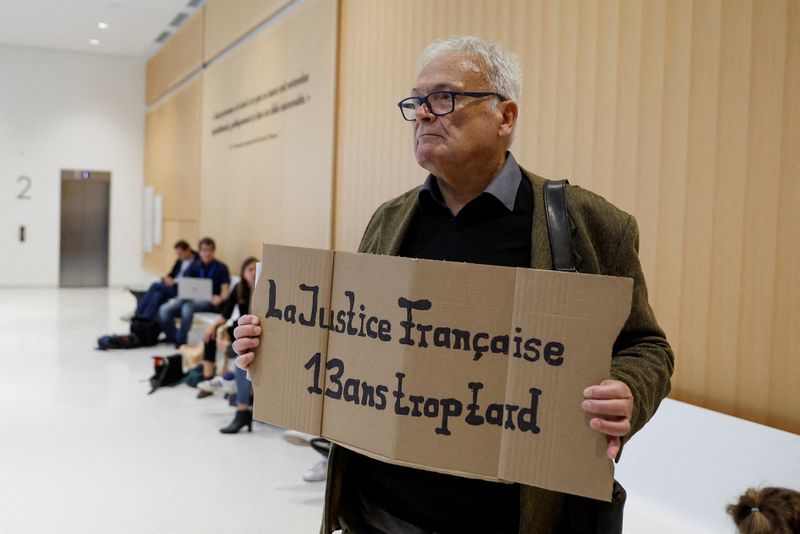 © Reuters. Wilfried Schmid, a family member of a victim, holds a placard that reads 