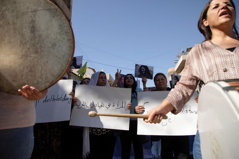 &copy; Reuters. FILE PHOTO: Women carry banners and play instruments during a protest over the death of 22-year-old Kurdish woman Mahsa Amini in Iran, in the Kurdish-controlled city of Qamishli, northeastern Syria September 26, 2022. The banner reads : 'Women are life an