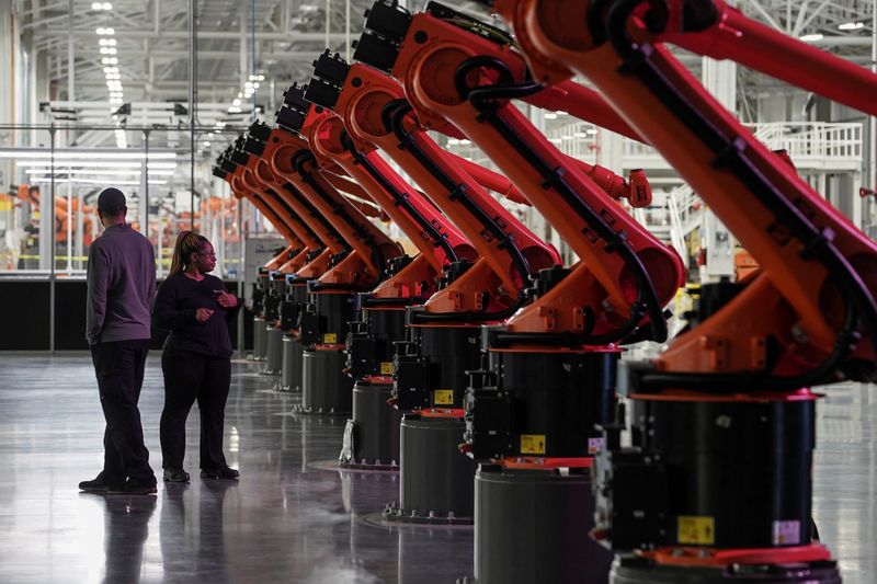 © Reuters. FILE PHOTO: People are seen next to robotic arms for a second battery tray assembly line at the opening of a Mercedes-Benz electric vehicle Battery Factory, marking one of only seven locations producing batteries for their fully electric Mercedes-EQ models, in Woodstock, Alabama, U.S., March 15, 2022. REUTERS/Elijah Nouvelage/File Photo