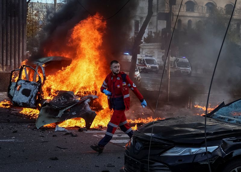 © Reuters. A medical worker walks near a burned car after Russian military strike, as Russia's invasion of Ukraine continues, in central Kyiv, Ukraine October 10, 2022.  REUTERS/Gleb Garanich