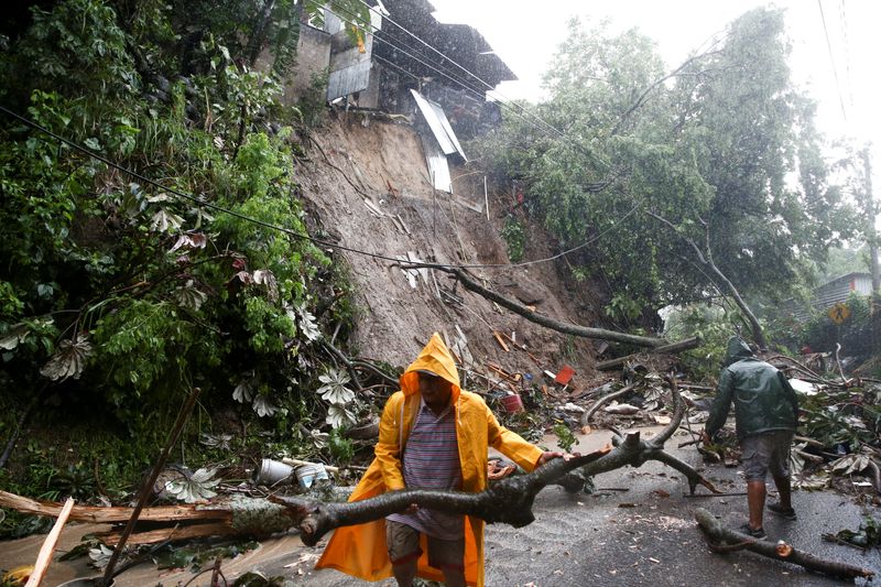 © Reuters. Residents clean a mudslide in a road while Tropical Storm Julia hits with wind and rain, in San Salvador, El Salvador, October 10, 2022. REUTERS/Jose Cabezas