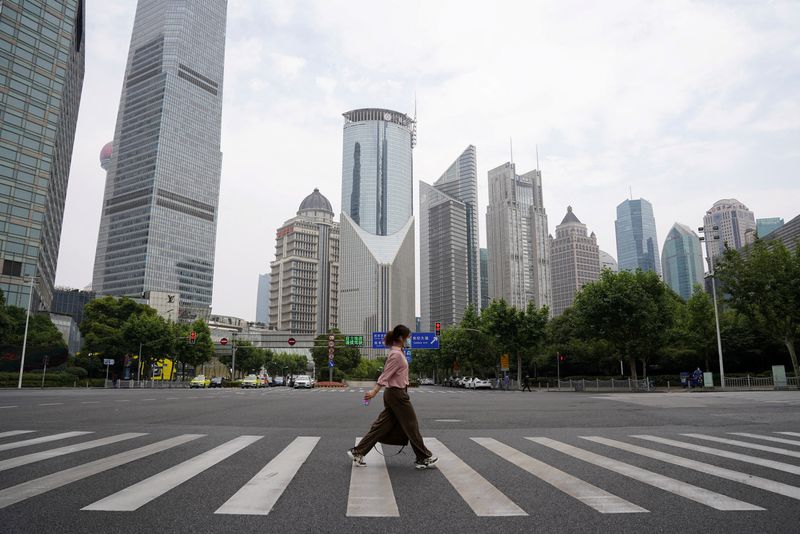 &copy; Reuters. FILE PHOTO: A pedestrian wearing a face mask crosses a road in front of office towers in Lujiazui financial district, after the lockdown placed to curb the coronavirus disease (COVID-19) outbreak was lifted in Shanghai, China June 1, 2022. REUTERS/Jason X