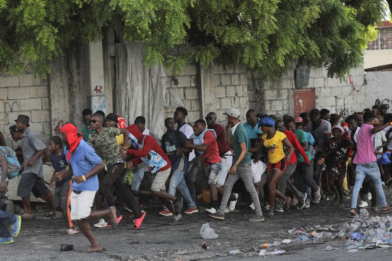 © Reuters. People walk away after hearing gunshots during a protest demanding the resignation of Haiti's Prime Minister Ariel Henry after weeks of shortages, in Port-au-Prince, Haiti October 10, 2022. REUTERS/Ralph Tedy Erol