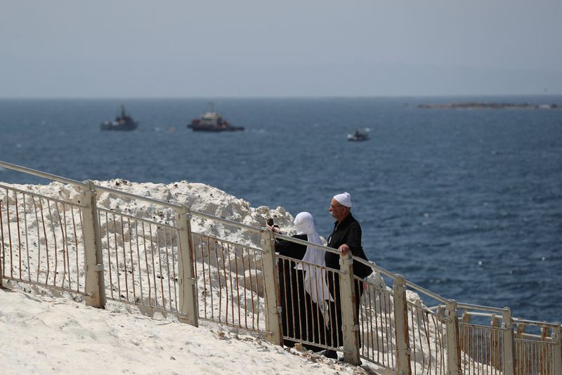 &copy; Reuters. FILE PHOTO: People walk as Israeli navy boats are seen in the Mediterranean Sea as seen from Rosh Hanikra, close to the Lebanese border, northern Israel May 4, 2021. REUTERS/Ammar Awad