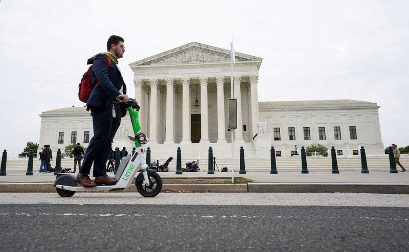 &copy; Reuters. FILE PHOTO: A man rides a scooter past the front of the U.S. Supreme Court building in Washington, U.S. September 30, 2022. REUTERS/Kevin Lamarque/File Photo