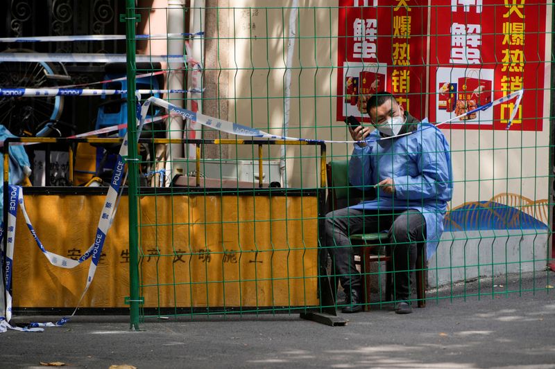 © Reuters. FILE PHOTO: A worker in a protective suit talks on a phone behind a barrier at a sealed area following the coronavirus disease (COVID-19) outbreak, in Shanghai, China October 11, 2022. REUTERS/Aly Song/File Photo