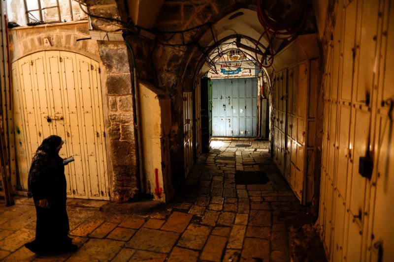 &copy; Reuters. A woman reads in a commercial thoroughfare which is closed in protest of an Israeli clampdown on Jerusalem's outlying Shuafat refugee camp after a Palestinian gunman carried out a deadly attack on a military checkpoint, in Jerusalem's Old City October 12,