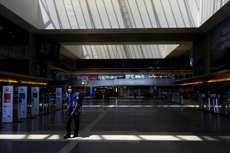 &copy; Reuters. FILE PHOTO: A Transportation Security Administration (TSA) agent wears a protective mask while walking through the Tom Bradley International Terminal (TBIT) at Los Angeles International Airport (LAX) on an unusually empty Memorial Day weekend during the o