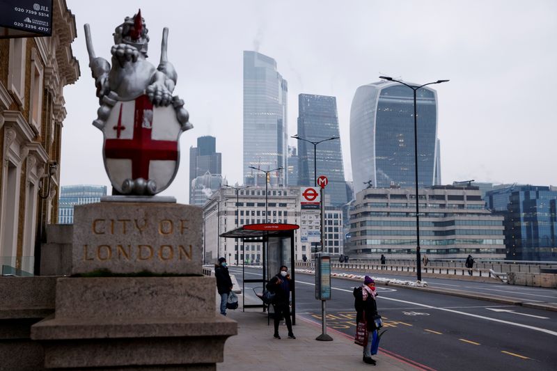 &copy; Reuters. FILE PHOTO: People wearing face masks wait at a bus stop on London Bridge, amid the outbreak of the coronavirus disease (COVID-19), with the City of London financial district in the background, Britain, January 8, 2021. REUTERS/John Sibley/File Photo