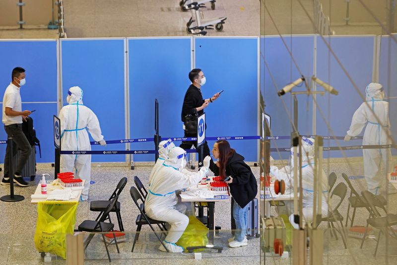 &copy; Reuters. FOTO DE ARCHIVO: Trabajadores médicos con trajes de protección recogen hisopos de los pasajeros para realizar pruebas de ácido nucleico, en una sala de llegadas del Aeropuerto Internacional de Shanghái Hongqiao, tras el brote de la enfermedad del coro